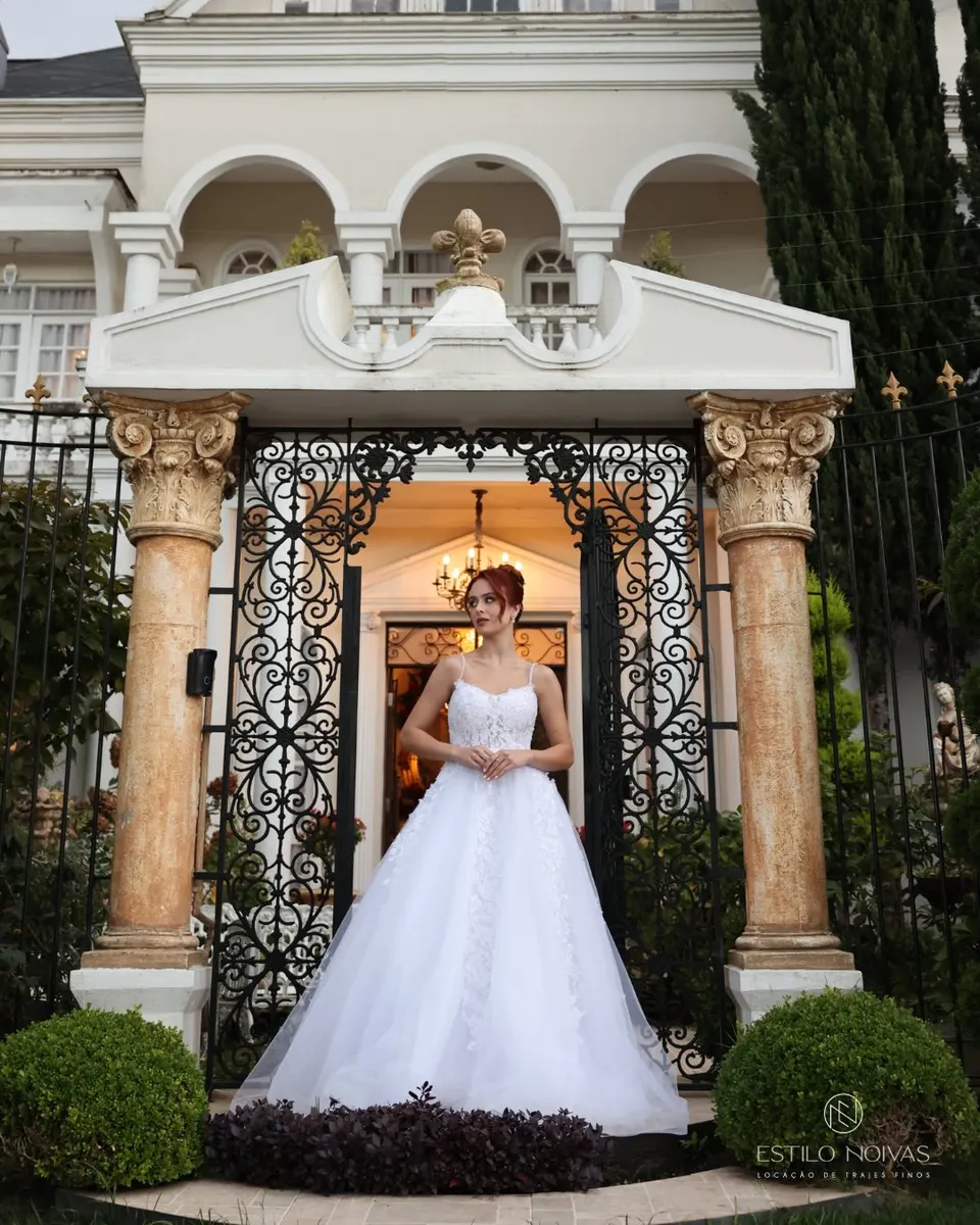 Noiva com vestido princesa sob pórtico com colunas e portão de ferro